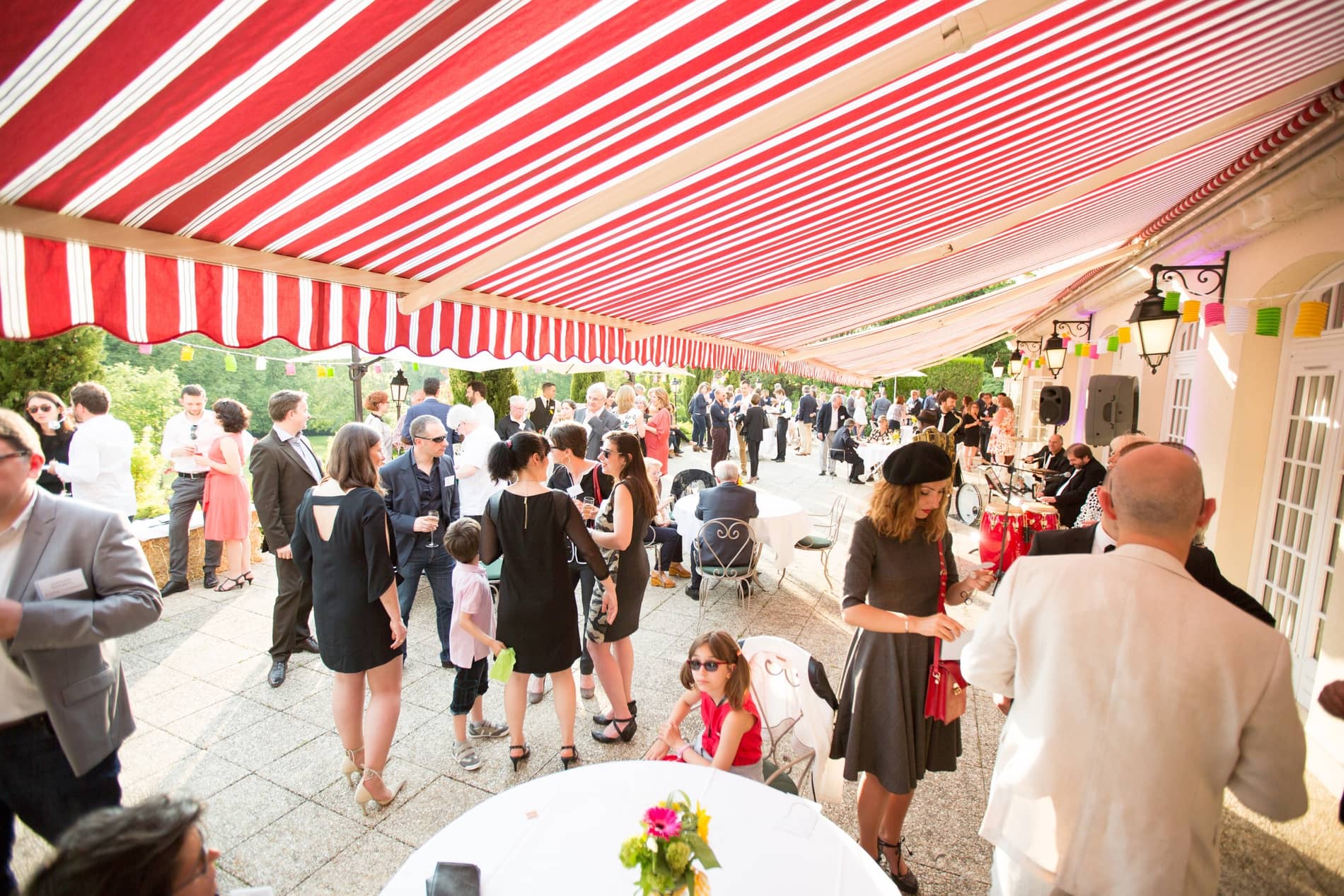 Cocktail de mariage sur la terrasse du Château de la Tour sous un auvent rayé rouge et blanc