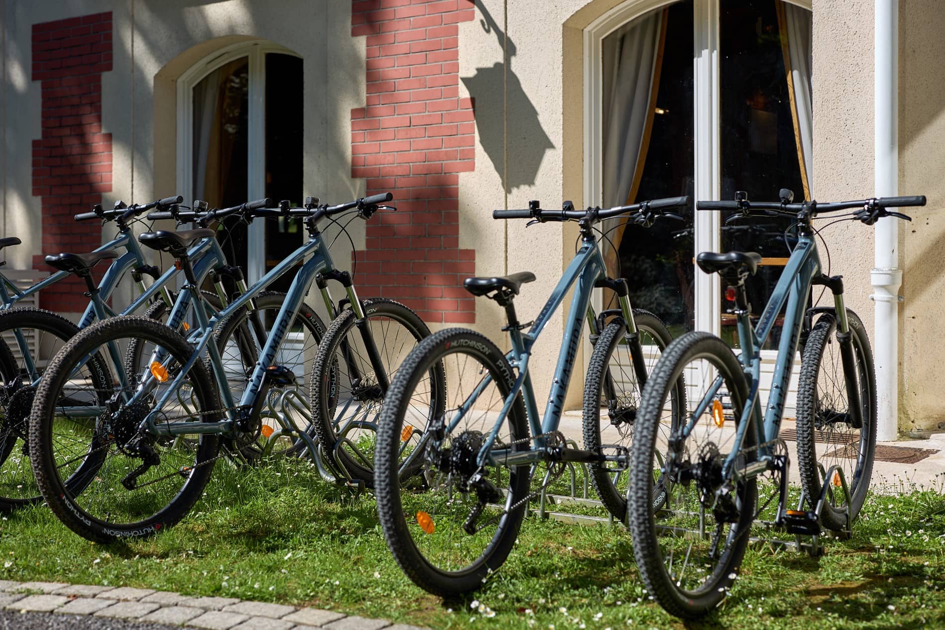 Vélos bleus disponibles pour les clients du Château de la Tour garés devant le bâtiment