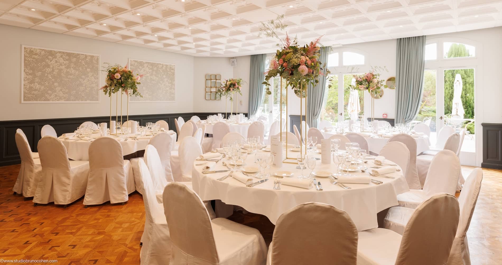 Salle de réception du Château de la Tour avec tables rondes dressées et centres floraux